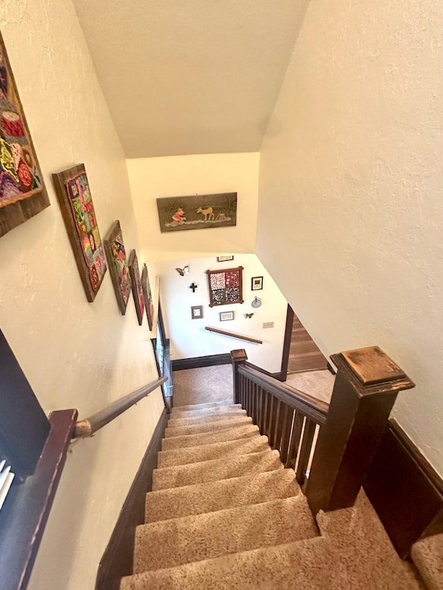 staircase with baseboards, carpet, and a textured wall