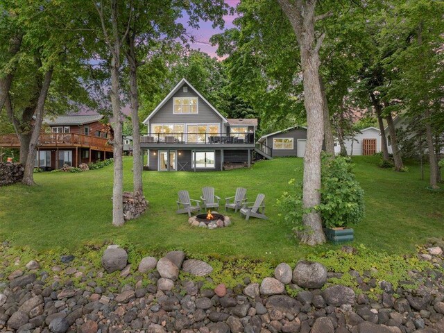 back of house with an outdoor fire pit, stairs, a lawn, a deck, and an outbuilding