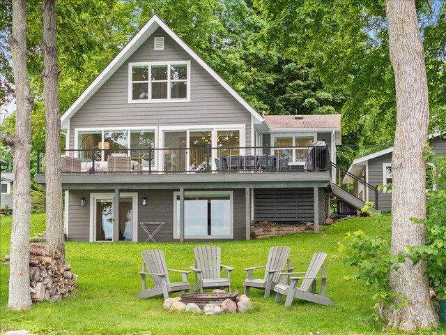 rear view of property featuring stairway, a fire pit, a lawn, and a wooden deck