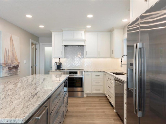 kitchen featuring white cabinetry, light wood-style floors, appliances with stainless steel finishes, and a sink
