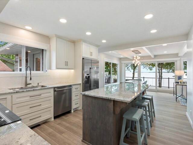 kitchen with a sink, stainless steel appliances, light wood-style floors, and a chandelier