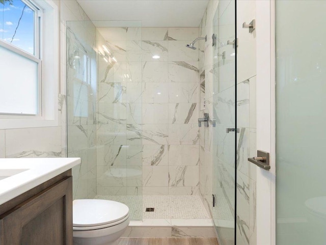 full bathroom with a marble finish shower, toilet, and vanity