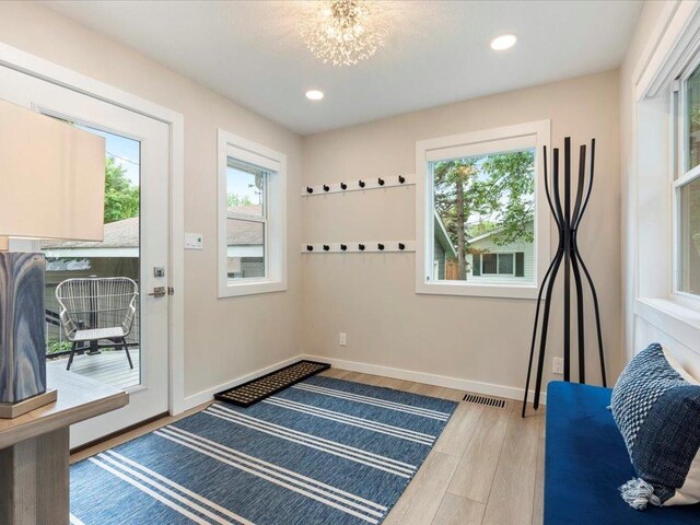 doorway with visible vents, wood finished floors, recessed lighting, baseboards, and a chandelier