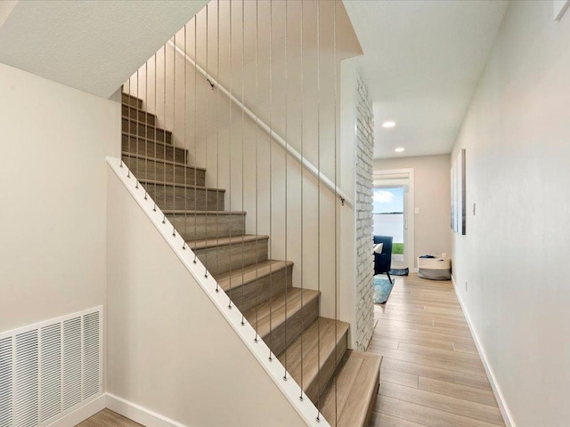 staircase featuring recessed lighting, visible vents, baseboards, and wood finished floors