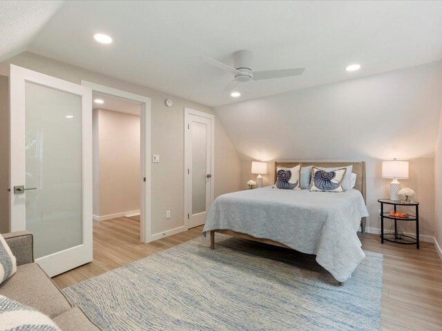 bedroom featuring light wood-type flooring, baseboards, and vaulted ceiling
