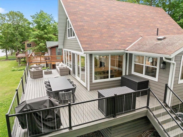 rear view of house featuring outdoor dining area, an outdoor hangout area, a lawn, and a deck