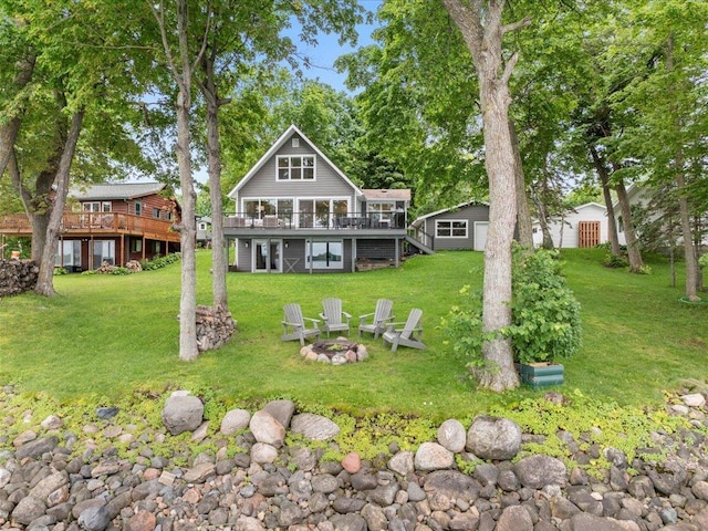 back of property with stairway, a yard, an outdoor structure, a fire pit, and a deck