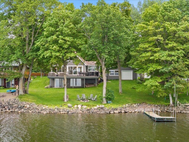 back of house featuring an outbuilding, a garage, a lawn, and a deck with water view