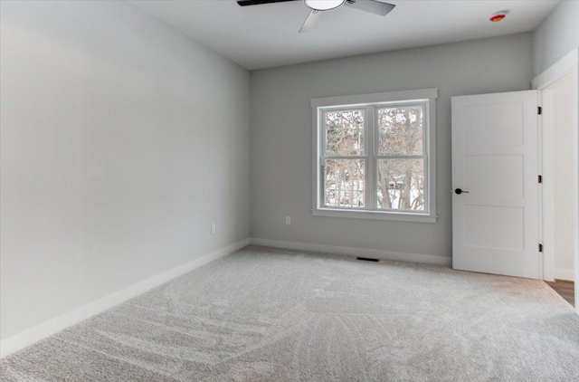 unfurnished room featuring visible vents, light colored carpet, baseboards, and a ceiling fan