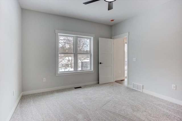 carpeted spare room featuring visible vents, baseboards, and ceiling fan