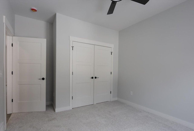 unfurnished bedroom with ceiling fan, light colored carpet, a closet, and baseboards