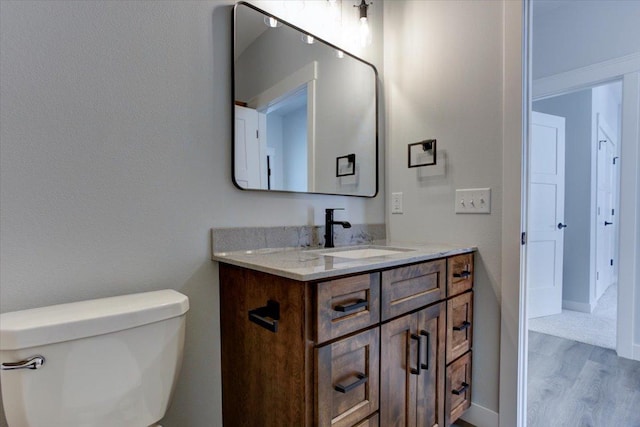 half bath featuring toilet, wood finished floors, and vanity