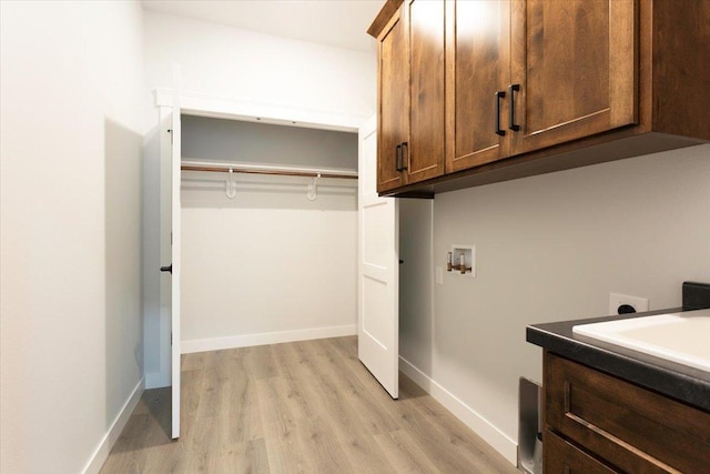 clothes washing area with cabinet space, light wood-style flooring, baseboards, and washer hookup