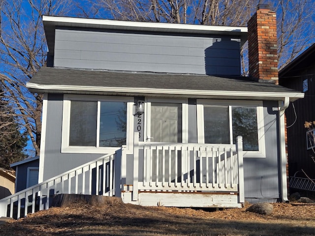 exterior space featuring a shingled roof, covered porch, and a chimney