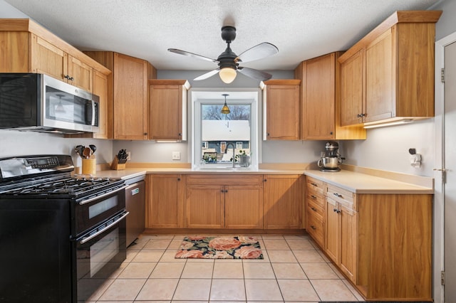 kitchen with ceiling fan, light countertops, light tile patterned floors, stainless steel appliances, and a sink