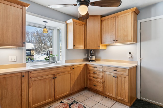 kitchen featuring light tile patterned floors, a ceiling fan, a sink, light countertops, and pendant lighting