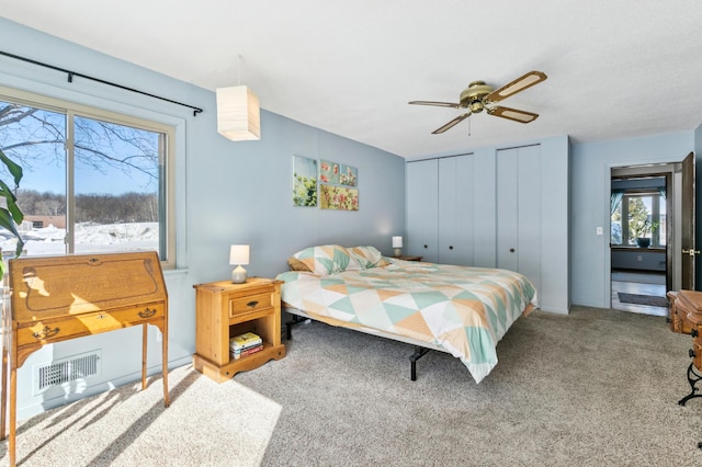 bedroom with visible vents, a ceiling fan, multiple closets, and carpet floors