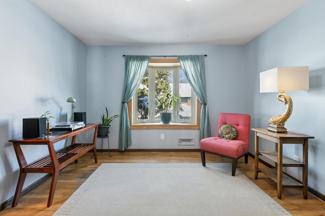 sitting room with visible vents, baseboards, and wood finished floors