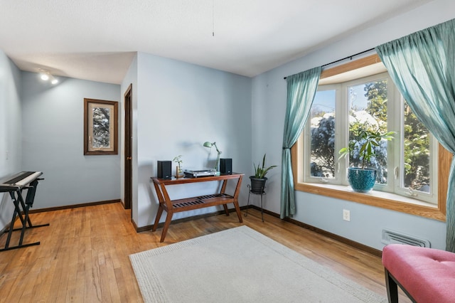 living area featuring visible vents, baseboards, and light wood finished floors