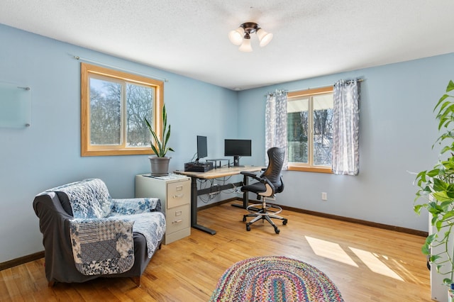 office with baseboards, a textured ceiling, and wood finished floors