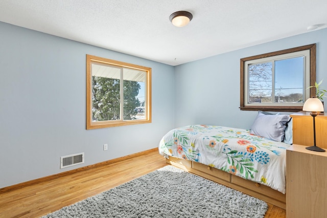 bedroom featuring wood finished floors, visible vents, and baseboards