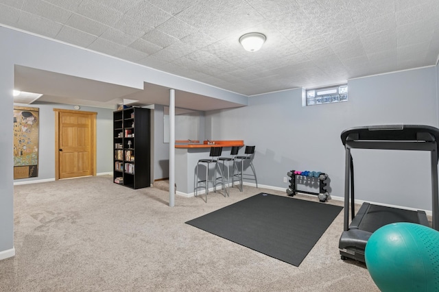 exercise area with baseboards, a dry bar, and carpet flooring