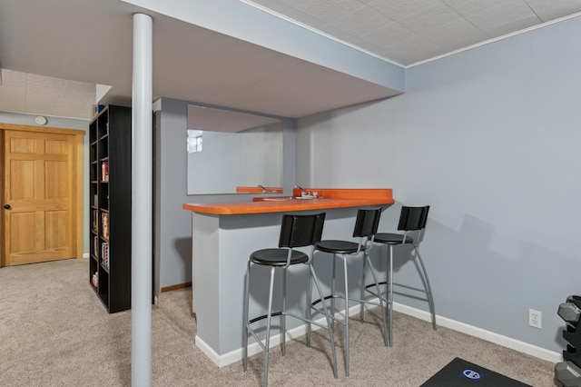 bar featuring wet bar, carpet flooring, and baseboards