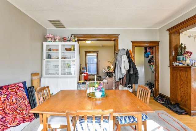 dining space featuring visible vents, a textured ceiling, and light wood finished floors