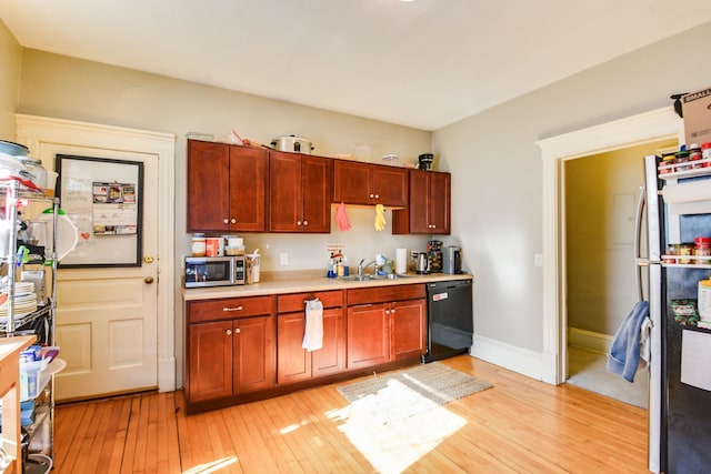 kitchen with stainless steel appliances, light countertops, a sink, and light wood-style flooring