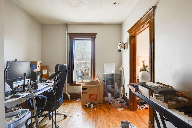 home office featuring light wood-type flooring and a textured ceiling