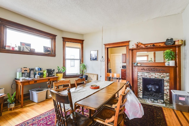 dining space featuring hardwood / wood-style flooring, a fireplace, and a textured ceiling