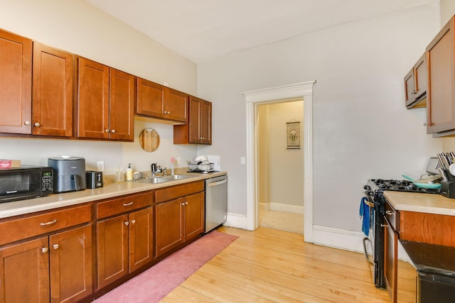 kitchen with gas range oven, light countertops, a sink, black microwave, and dishwasher