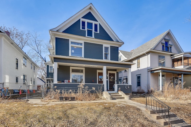 american foursquare style home with a gate, fence, and a porch