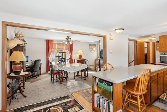 kitchen featuring light wood-style floors, a kitchen breakfast bar, light countertops, and brown cabinetry