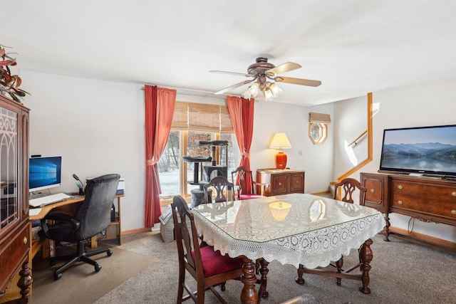 carpeted dining room with a ceiling fan, baseboards, and stairs