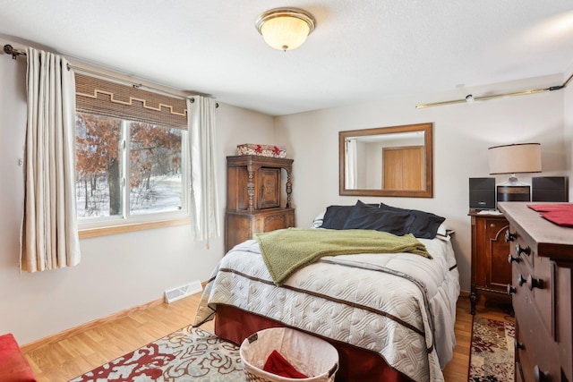 bedroom featuring baseboards, visible vents, and wood finished floors