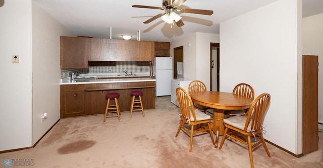 dining room with baseboards, light colored carpet, and a ceiling fan