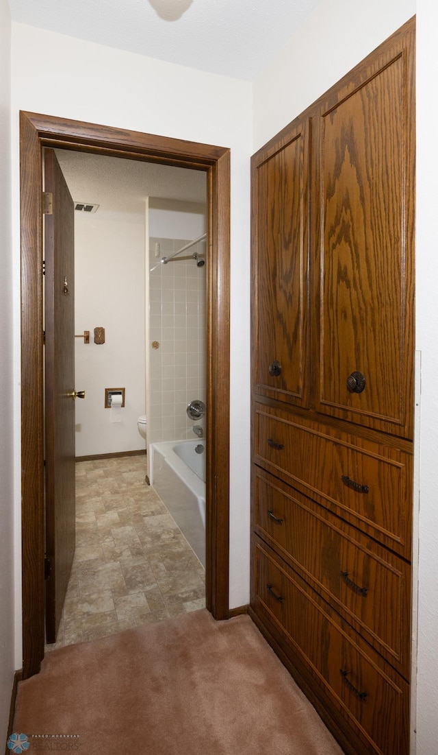 corridor featuring visible vents, baseboards, and light colored carpet