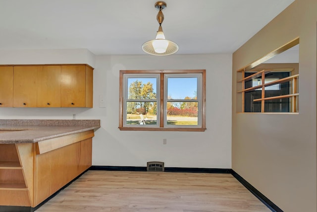 unfurnished dining area with visible vents, light wood-style flooring, and baseboards