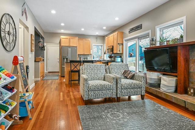 living area featuring recessed lighting, baseboards, and light wood finished floors