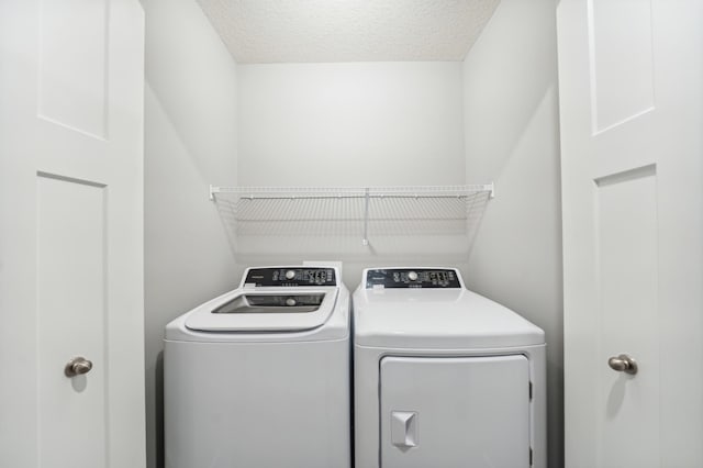 laundry area with laundry area, washer and clothes dryer, and a textured ceiling