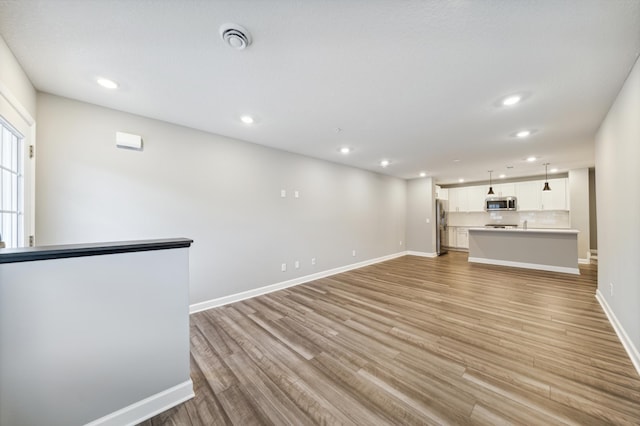 unfurnished living room featuring light wood-type flooring, visible vents, baseboards, and recessed lighting