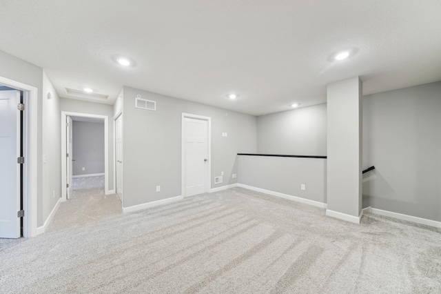 basement featuring light colored carpet, recessed lighting, visible vents, and baseboards