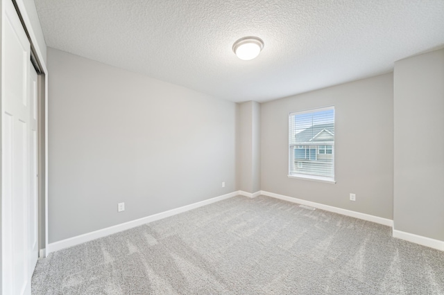 unfurnished bedroom featuring carpet, a closet, a textured ceiling, and baseboards