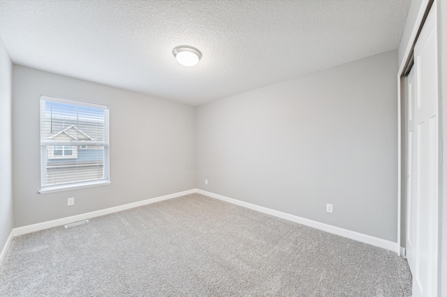 unfurnished bedroom featuring baseboards, visible vents, carpet, a textured ceiling, and a closet