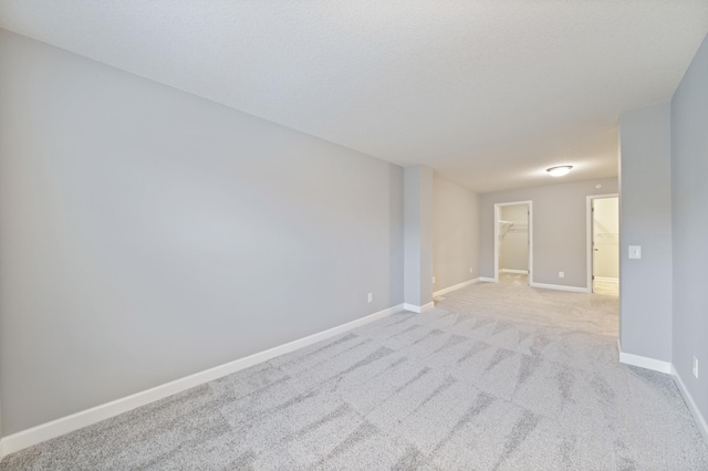 empty room featuring light carpet, baseboards, and a textured ceiling