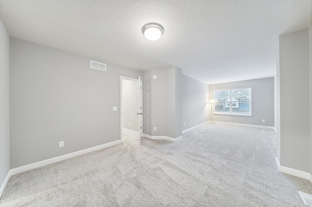 carpeted empty room with a textured ceiling, visible vents, and baseboards