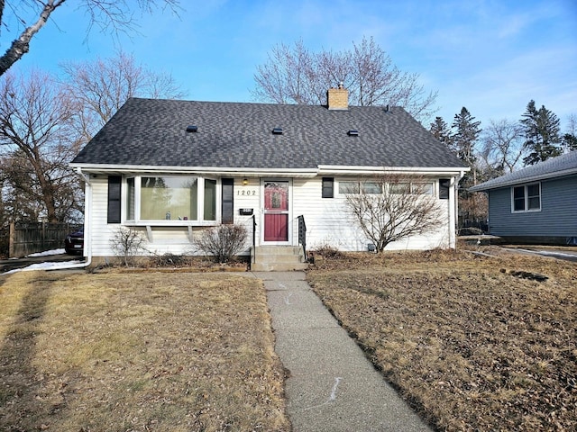 ranch-style house featuring a shingled roof, a front lawn, fence, and a chimney