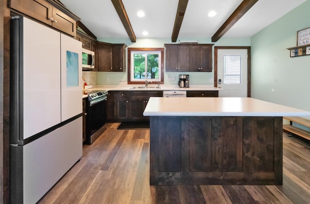 kitchen with appliances with stainless steel finishes, light countertops, a sink, and dark brown cabinetry