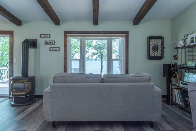 living room featuring dark wood finished floors, a wood stove, and beamed ceiling